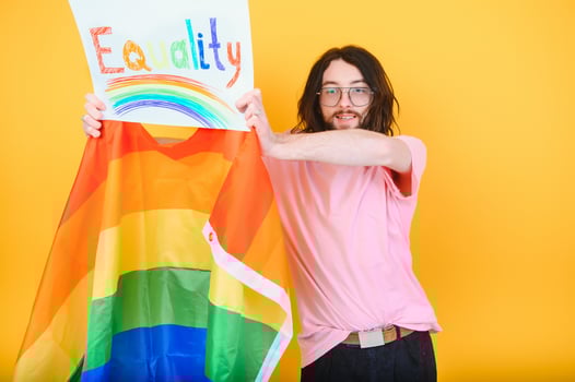 Handsome young man with pride movement LGBT Rainbow flag on shoulder against white background. Man with a gay pride flag. photo