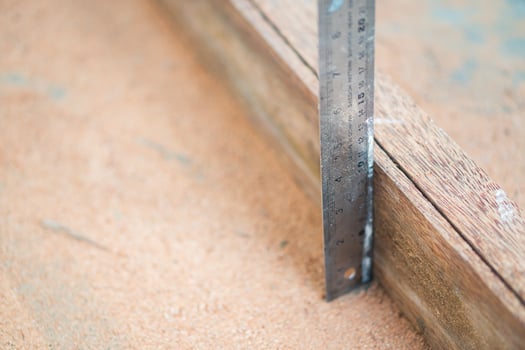Metal ruler measuring wooden plank on sandy surface photo