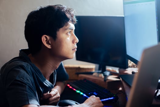 Young man focused on computer screen in dimly lit room photo