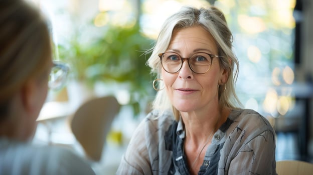 Woman in glasses conversing with lady in cafe photo