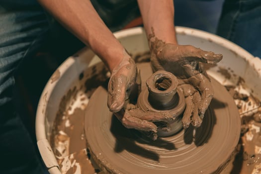 Hands Shaping Clay Pot on Pottery Wheel in Workshop photo
