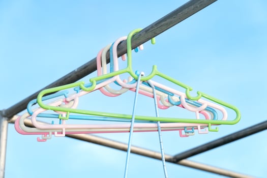 Colorful plastic hangers for hanging small outfits. Hanging on outdoor steel structure. The background image is a clear blue sky. photo