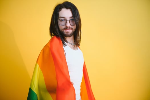 Gay man hold rainbow striped flag isolated on colored background studio portrait. People lifestyle fashion lgbtq concept photo
