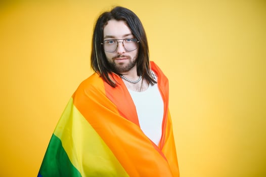 Gay man hold rainbow striped flag isolated on colored background studio portrait. People lifestyle fashion lgbtq concept photo