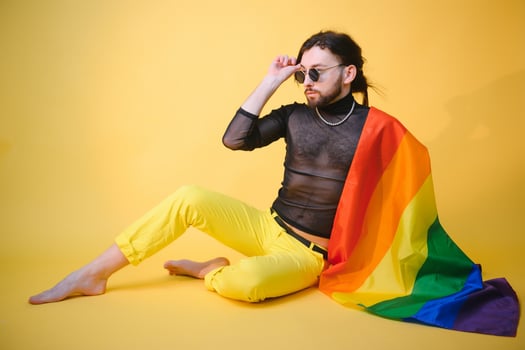 Gay man hold rainbow striped flag isolated on colored background studio portrait. People lifestyle fashion lgbtq concept photo
