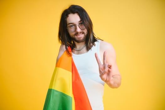 Gay man hold rainbow striped flag isolated on colored background studio portrait. People lifestyle fashion lgbtq concept photo