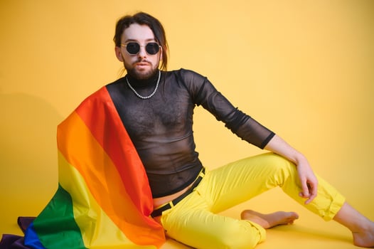 Handsome young man with pride movement LGBT Rainbow flag on shoulder against white background. Man with a gay pride flag. photo