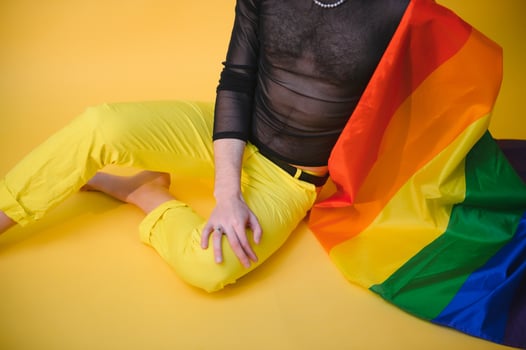 Handsome young man with pride movement LGBT Rainbow flag on shoulder against white background. Man with a gay pride flag. photo