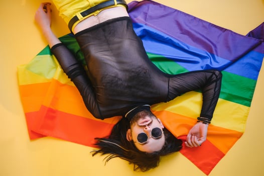 Gay man hold rainbow striped flag isolated on colored background studio portrait. People lifestyle fashion lgbtq concept photo