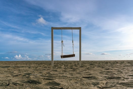 Wooden rope swing at the beach at sunset. Wood swing at the sandy beach in Meulaboh, Aceh Indonesia. Beach landscape with blue sky background photo