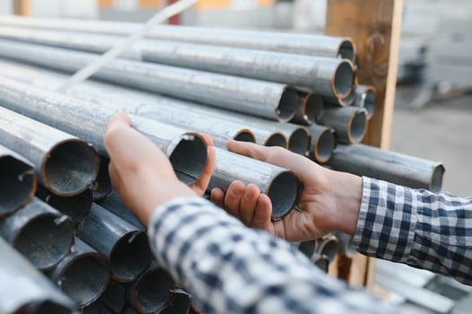 a worker holds metal pipes in a factory warehouse. Metal rolling photo