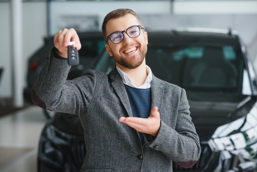 Portrait of a handsome salesman in the suit standing near the car in the showroom photo