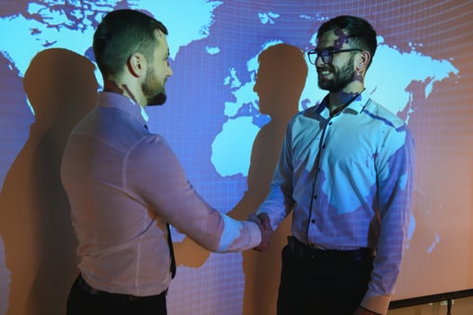 Handshake with map of the world in background. two businessmen on the background of the world map shake hands, the concept of international relations photo