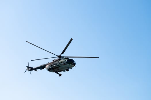 Military large aircraft flies over a clear blue sky, close-up photo