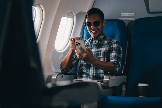 Traveling and technology. happy young businessman working on laptop computer and smartphone while sitting in airplane. photo