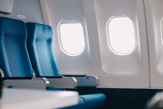 Side view millennial businessman drinking coffee, and using laptop while sitting comfortable seat on airplane cabin photo