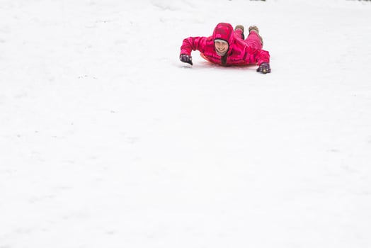 little girl riding on snow slides in winter time photo