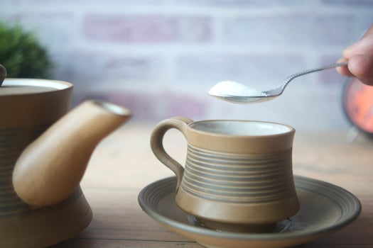 pouring white sugar in a tea cup photo