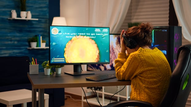 Upset professional woman gamer wearing headset losing shooter game round in cybersport competition. Tired player gaming online games on personal computer with modern technology network wireless photo