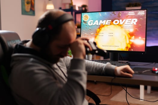 Addicted gamer losing space shooter videogame using headphones and wireless joystick. Upset player . Defeated gamer using professional equipment for online tournament late at night in gaming room photo