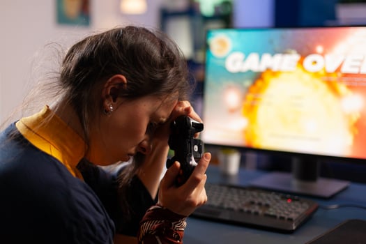 Professional gamer keeping her controller on hand after losing space shooter game using wireless joystick . Competitive player using modern equipment for online championship photo