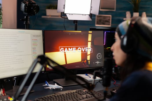 Game over for streamer talking into microphone with other players via streaming chat wearing headphones. Online cyber performer during gaming tournament using powerful PC with RGB photo