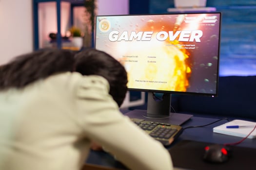 Gamer over for sad african gamer after losing championship sitting with head on the table. Angry professional gamer gaming over during an space shooter online game. photo