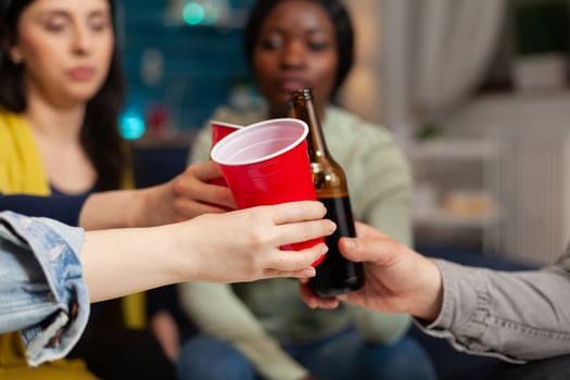 Multi ethnic friends hanging out sitting on couch chatting clinking beer cups. Group of multiracial people spending time together sitting on couch late at night in living room. photo