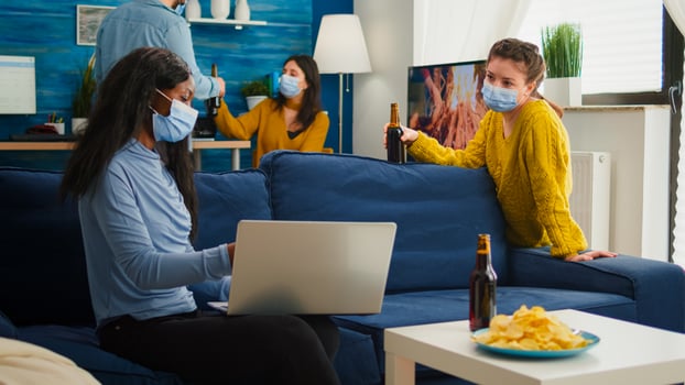 Happy african woman showing on laptop to friend sitting in living room keeping social distancing due to coronavirus pandemic to prevent virus spread. People socializing during covid 19 outbreak photo