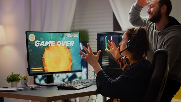 Stressed couple gamers losing space shooter game playing on RGB powerful computer while streaming online competition. Pro cyber woman with headset performing from home during virtual tournament photo