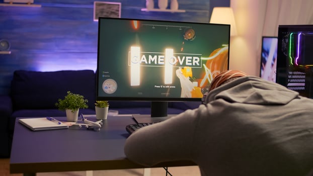 Over shoulder shot of man after losing at games on computer using professional RGB equipment. Defeted player playing first person shooter games using modern technology network wireless photo