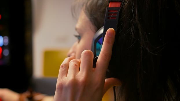 Closeup of professional gamer wearing headset and talking with other players into microphone during esport tournament. Player sitting on gaming chair playing space shooter game using RGB equipment photo