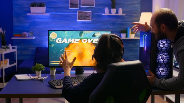 Pro gamer losing space shooter game tournament using professional equipment. Game over for couple of players use headphones for gaming competition late at night in living room photo