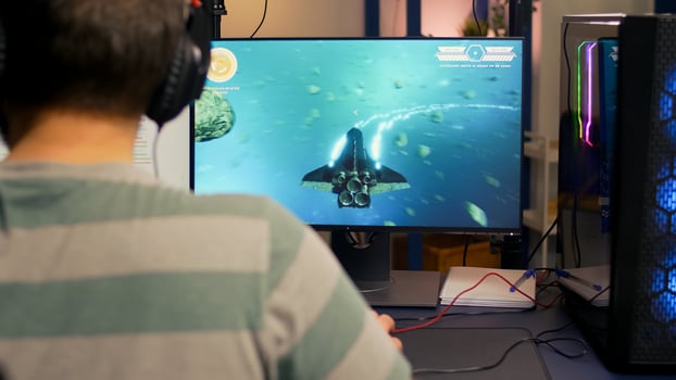 Over shoulder footage of professional streamer playing digital space shooter games on computer using headphones, microphone and mouse. Videogamer man streaming online games in room with RGB photo