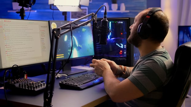 Back shot of pro streamer playing graphics cyber space shooter games using wireless joystick. Gamer performing on powerful pc talking with players on chat open during professional competition photo