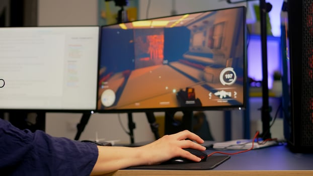 Close-up of pro streamer use RGB mouse during first person shooter game tournament. Gamer sitting on gaming chair during streaming competition in room with neon lights photo
