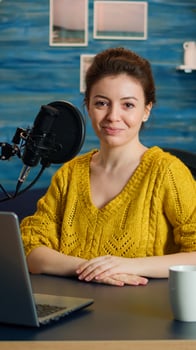Portrait of young vlogger working in cozy studio, smiling at camera ready to start new podcast show. On-air online production internet broadcast show host streaming web content record digital blog photo