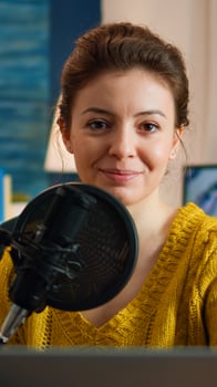 Woman blogger sitting in home studio looking at camera preapring for live recording podcast show. On-air online production internet broadcast host streaming web content record digital blog photo