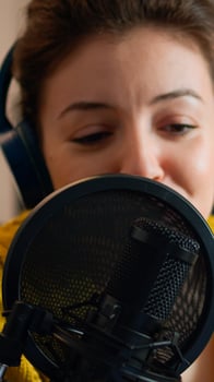 Influencer talking on professional microphone during livestreaming recording vlog in living room. On-air online production internet broadcast show host streaming live content for social media photo