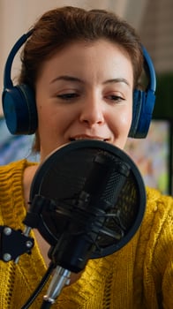 Famous woman arranging professional microphone and smiling while recording podcast for social media from home in night. On-air online production internet broadcast show host streaming live content photo