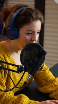 Blogger speaking at microphone with followers livestreaming typing on laptop. Online show On-air production internet broadcast host streaming live content, recording digital social media communication photo