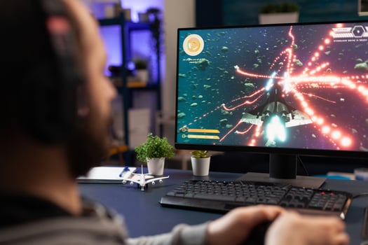 Close up of man using joystick to play online games on computer. Person playing game with joystick and headphones in front of monitor. Player having gaming equipment for fun. photo