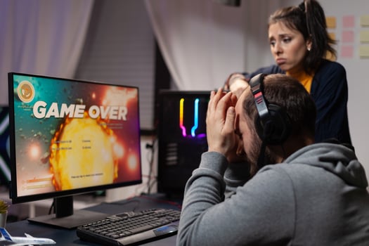 Couple of gamers feeling sad about losing games in front of computer. Woman comforting man about lost game online, having gaming equipment and headphones to play for leisure. photo