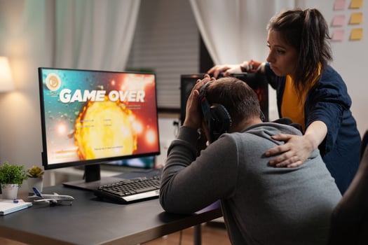 Couple feeling sad about losing games play in front of computer. Woman comforting man about lost game online, having gaming equipment and headphones, playing for leisure. photo