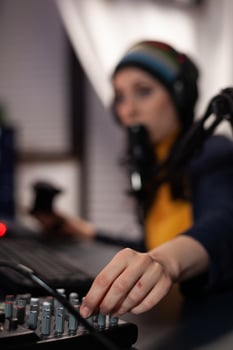 Close up of woman using streaming equipment live with headphones and microphone. Gamer talking to audience on online broadcast, live streaming on computer. Streamer with electronic gadget photo
