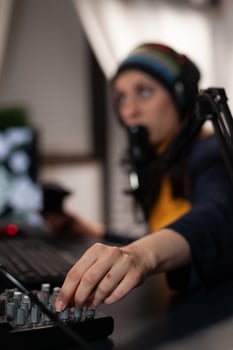 Close up of adult using streaming equipment on desk with headphones and microphone. Gamer talking to audience on broadcast, live streaming on computer. Streamer with electronic gadget photo