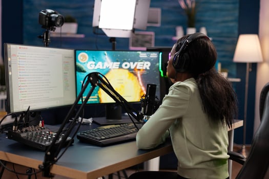 Sad nervous pro gamer sitting at gaming desk playing space shooter videogames losing online games championship. Upset esport woman streaming live using RGB computer equipment, Game over on screen photo