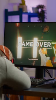 Game over for sad gamer playing shooter games on powerful computer using RGB keyboard in gaming room. Defeated man with headphones streaming online cyber performing through online tournament photo
