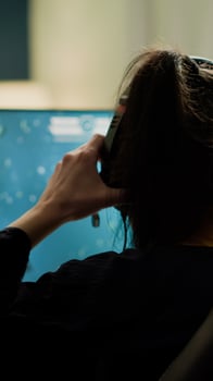 Competitive gamer streatching on gaming chair, putting headphone before playing space shooter games on RGB powerful computer. Pro woman streaming cyber performing during online esports tournament photo