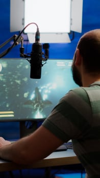 Streamer cyber performing space shooter game on RGB powerful computer talking with players on stream chat and microphone during professional competition. Player man streaming in home studio photo